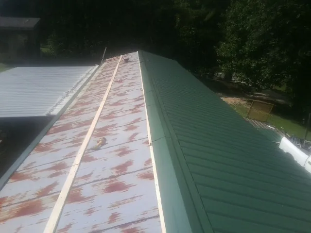 Old rusted panels beside newly installed green metal roofing — Wind Damage Roof Repair by Roofing Brothers in Williamston