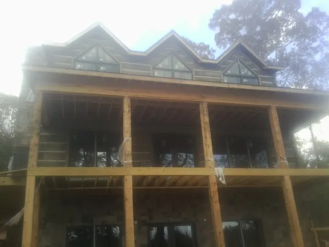 Dormers and porch framing on a large log home under construction — Roof Coating work by our crew in Williamston